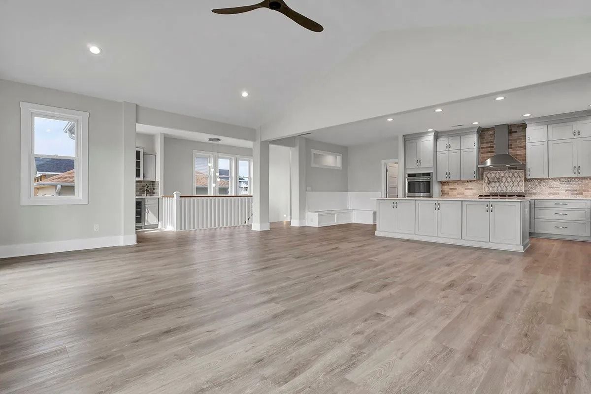 Spacious, light-filled open-concept kitchen and living area with gray cabinets, wood flooring, and recessed lighting.