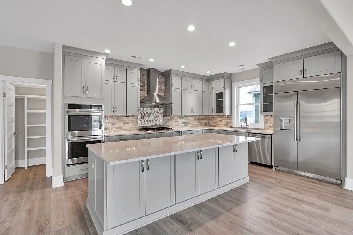 Gray kitchen with an island, cabinets, stainless steel appliances, and wood flooring.