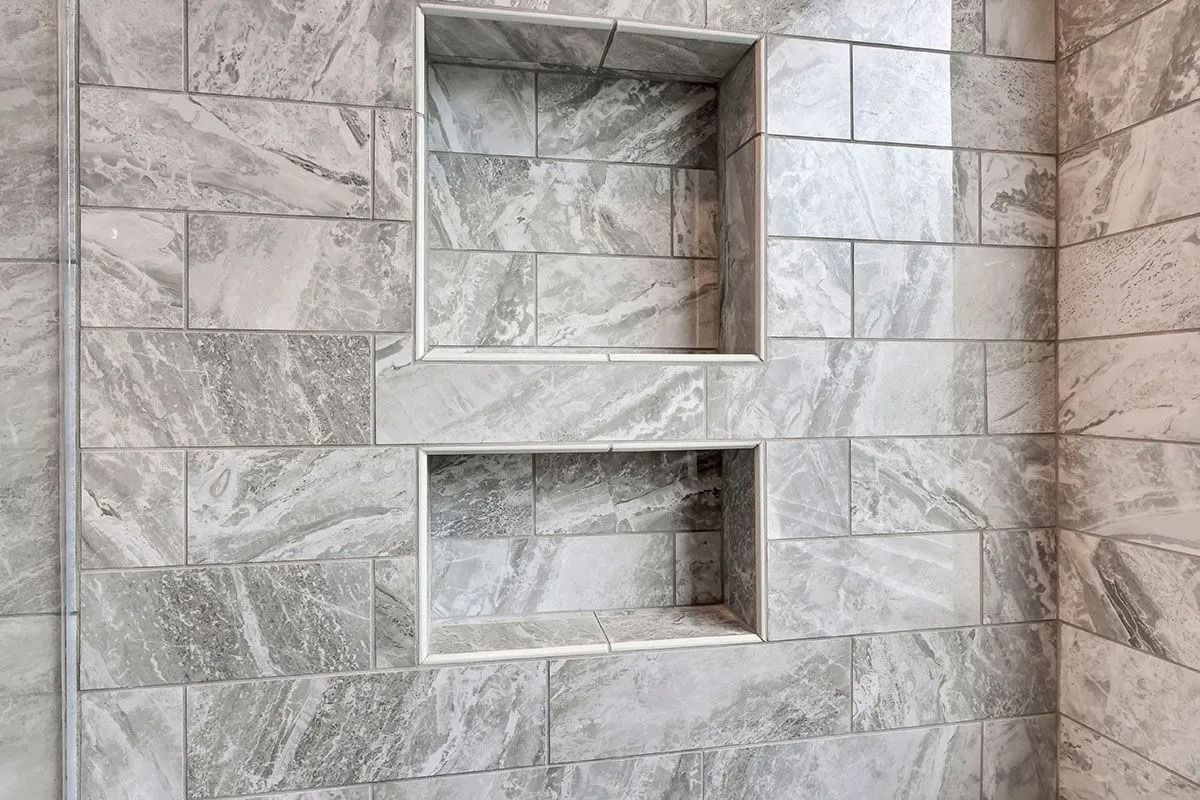 Two tiled shower niches in a gray marble-look wall.