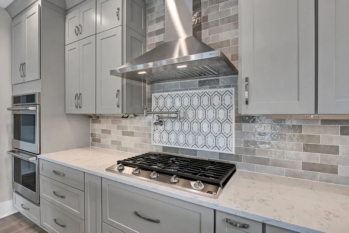 Modern kitchen with grey cabinets, stainless steel appliances, and white countertops.