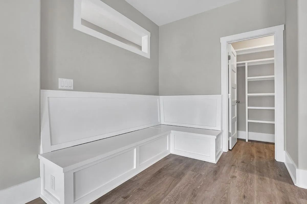 Empty, light gray entryway with a white built-in bench and a closet.