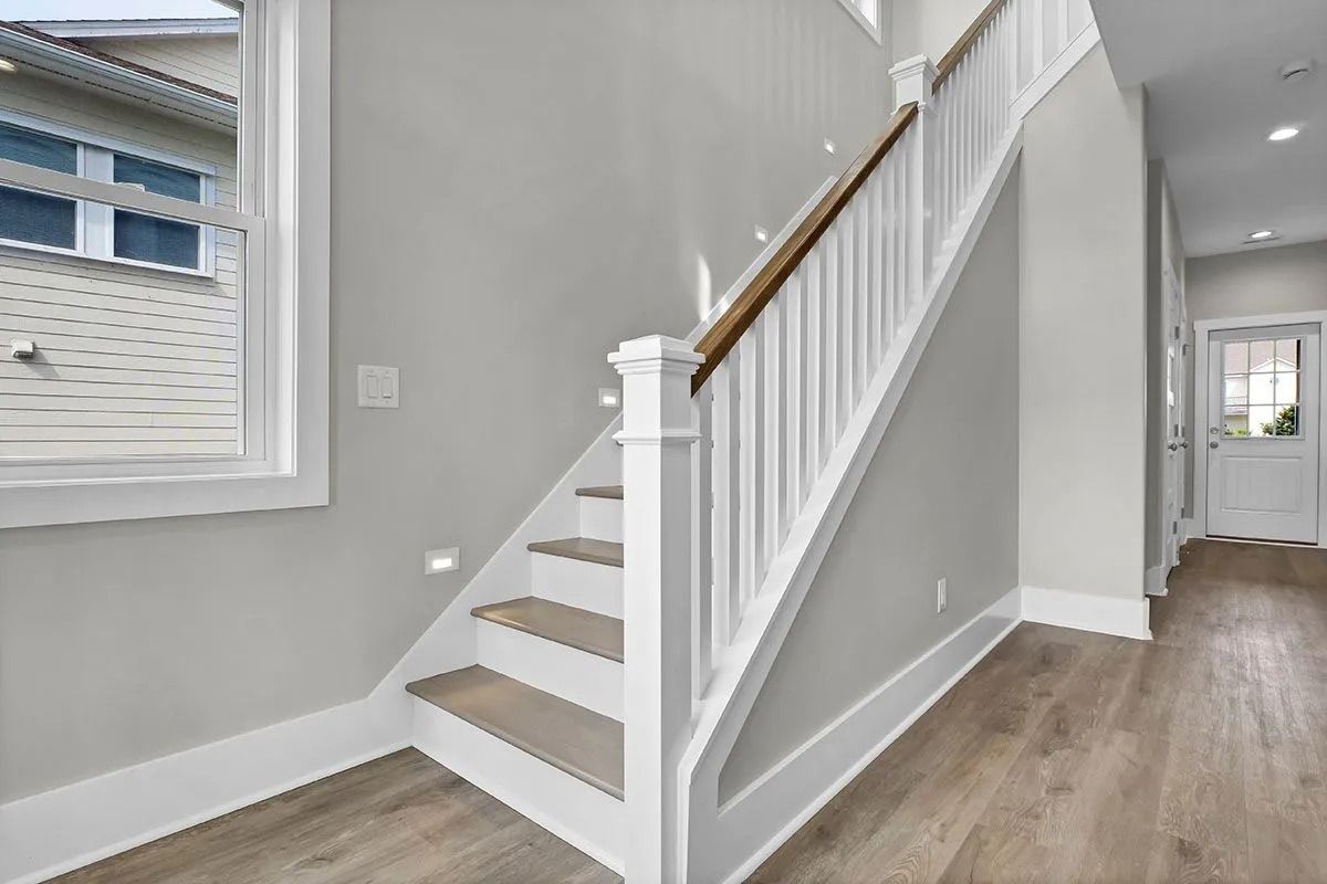 Staircase with white railing, wood steps, and gray walls in a modern home.