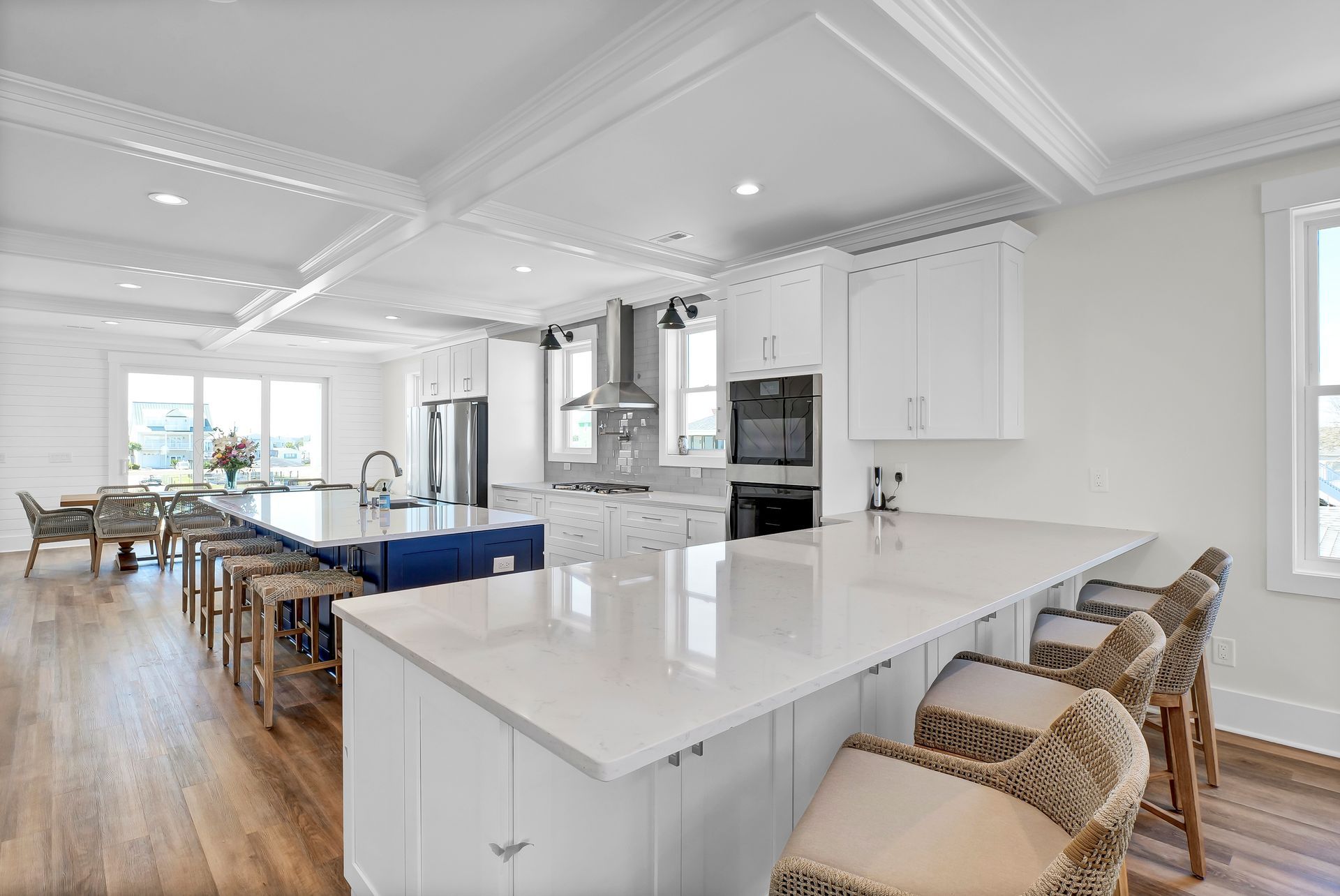 Spacious white kitchen with two islands, seating, and stainless steel appliances.