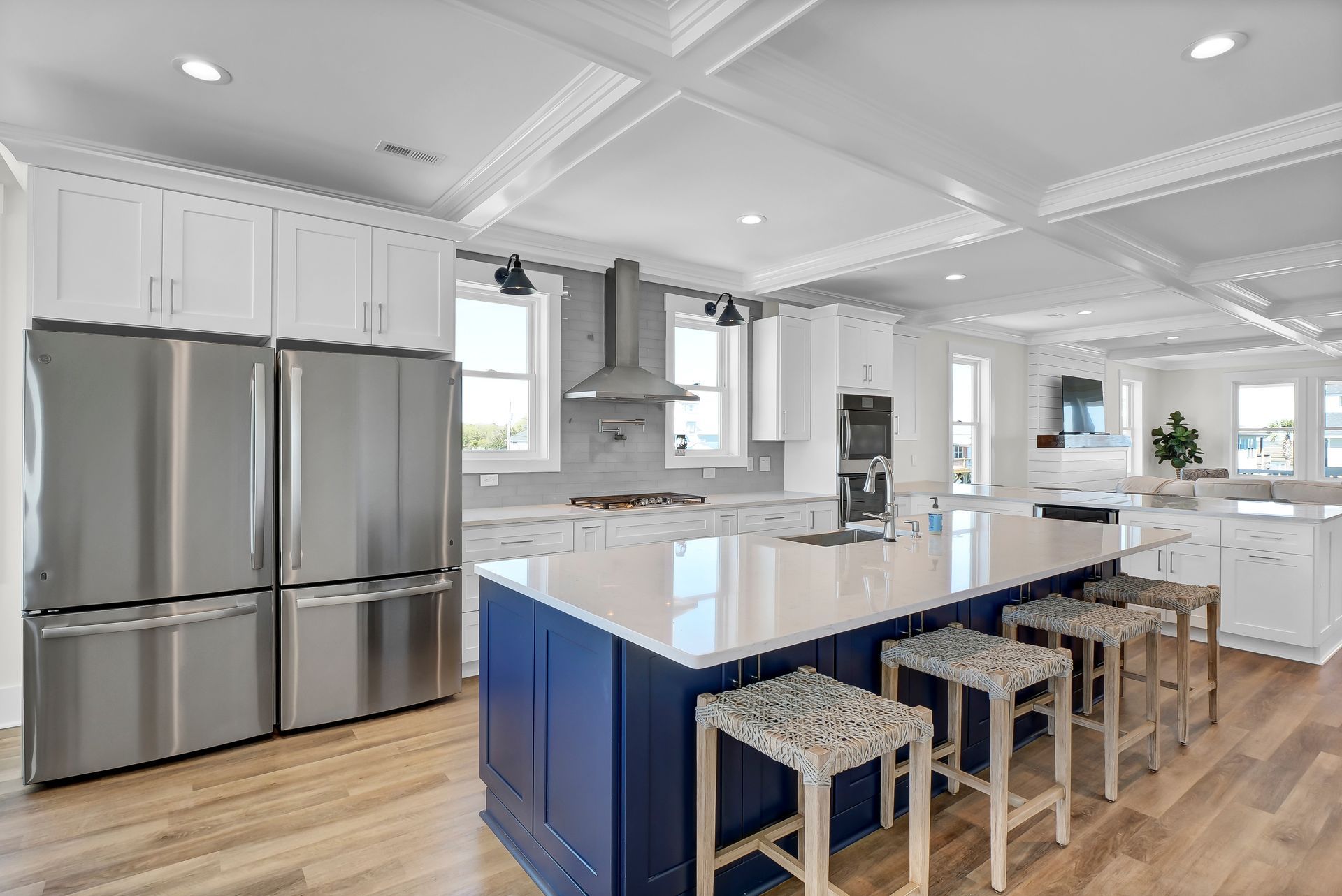 Modern kitchen with white cabinets, stainless steel appliances, blue island, and light wood floors.