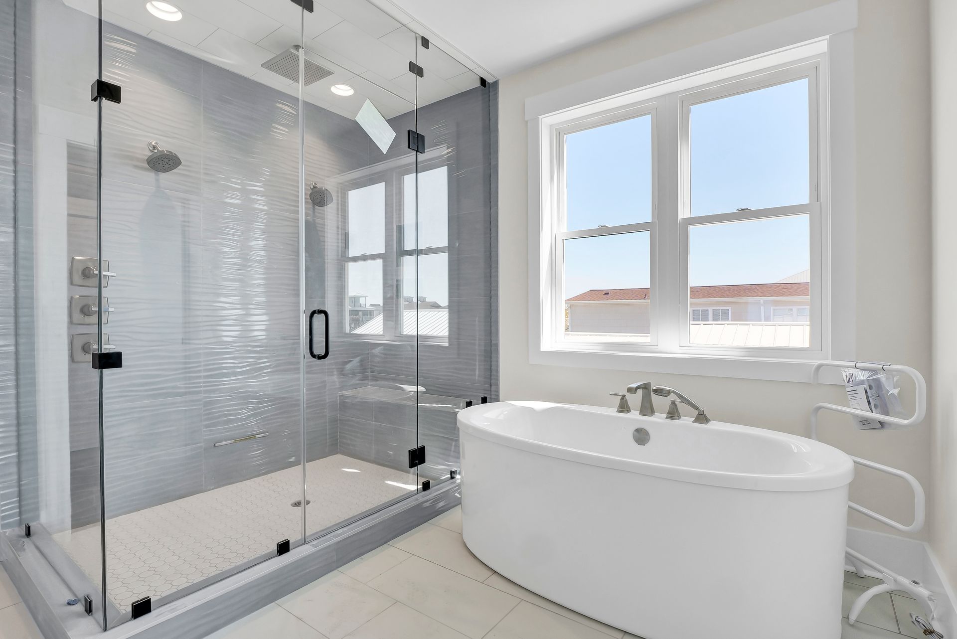 Modern bathroom with a glass-enclosed shower, freestanding tub, and a window.