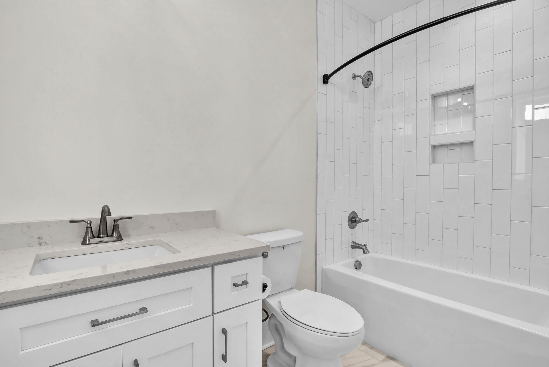 White bathroom with vanity, toilet, and bathtub/shower combo.