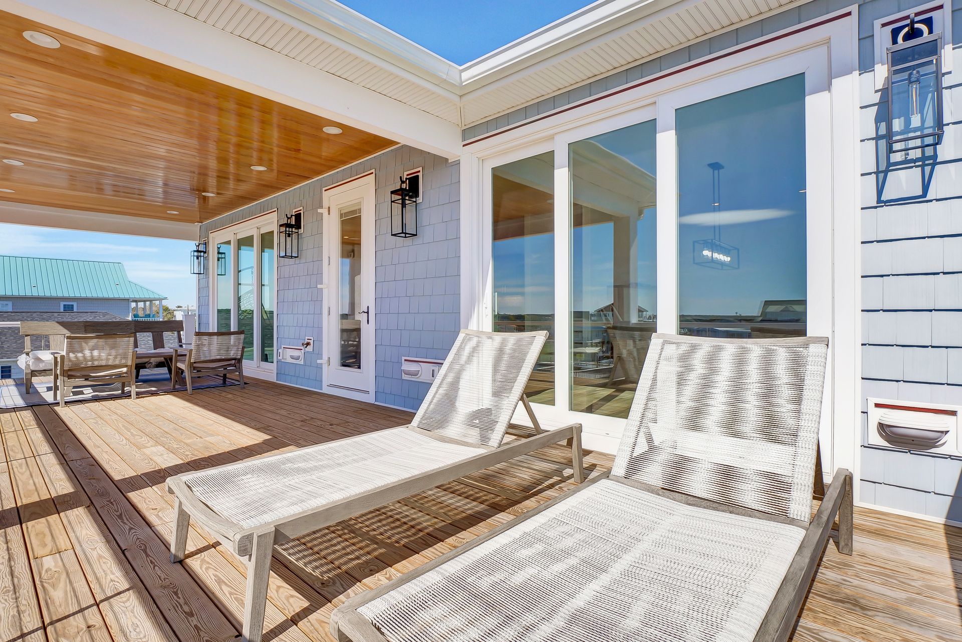 A deck with two lounge chairs, sliding glass doors, and a partial ocean view.