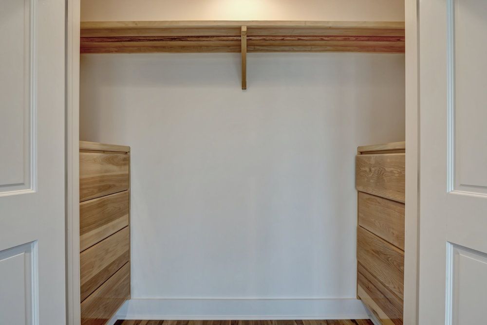 Empty closet interior with white walls, wood trim, and two built-in drawer units.