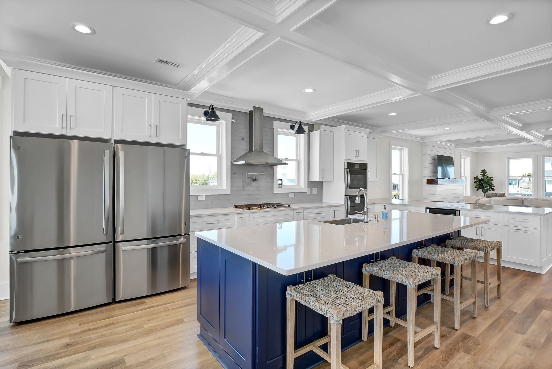 Spacious white kitchen with a blue island and stainless steel appliances.