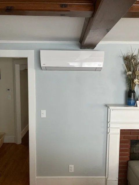 A living room with a fireplace and a wall mounted air conditioner.