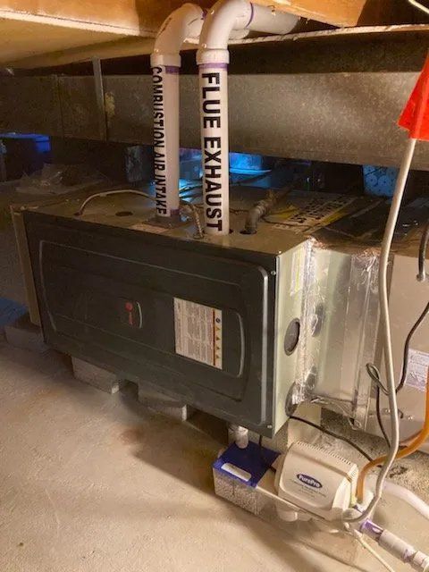 A flue exhaust pipe is attached to a furnace in a basement