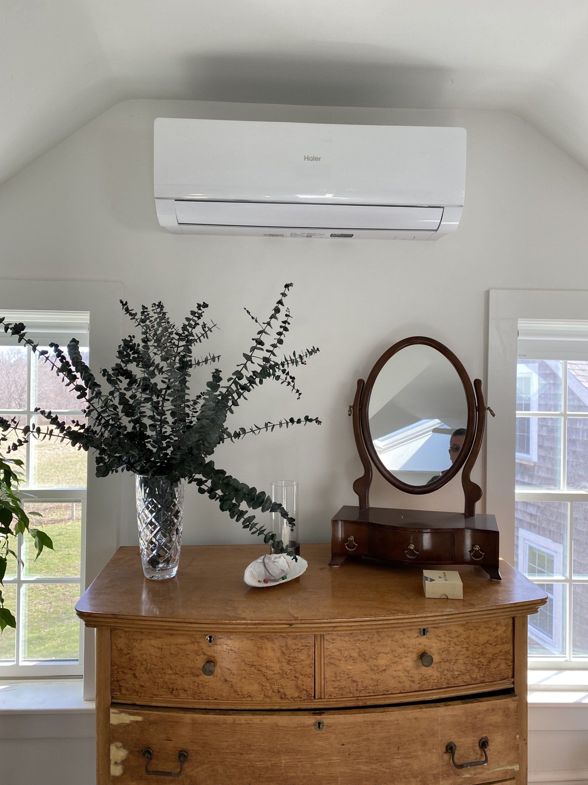 A dresser with a vase of flowers and a mirror on it