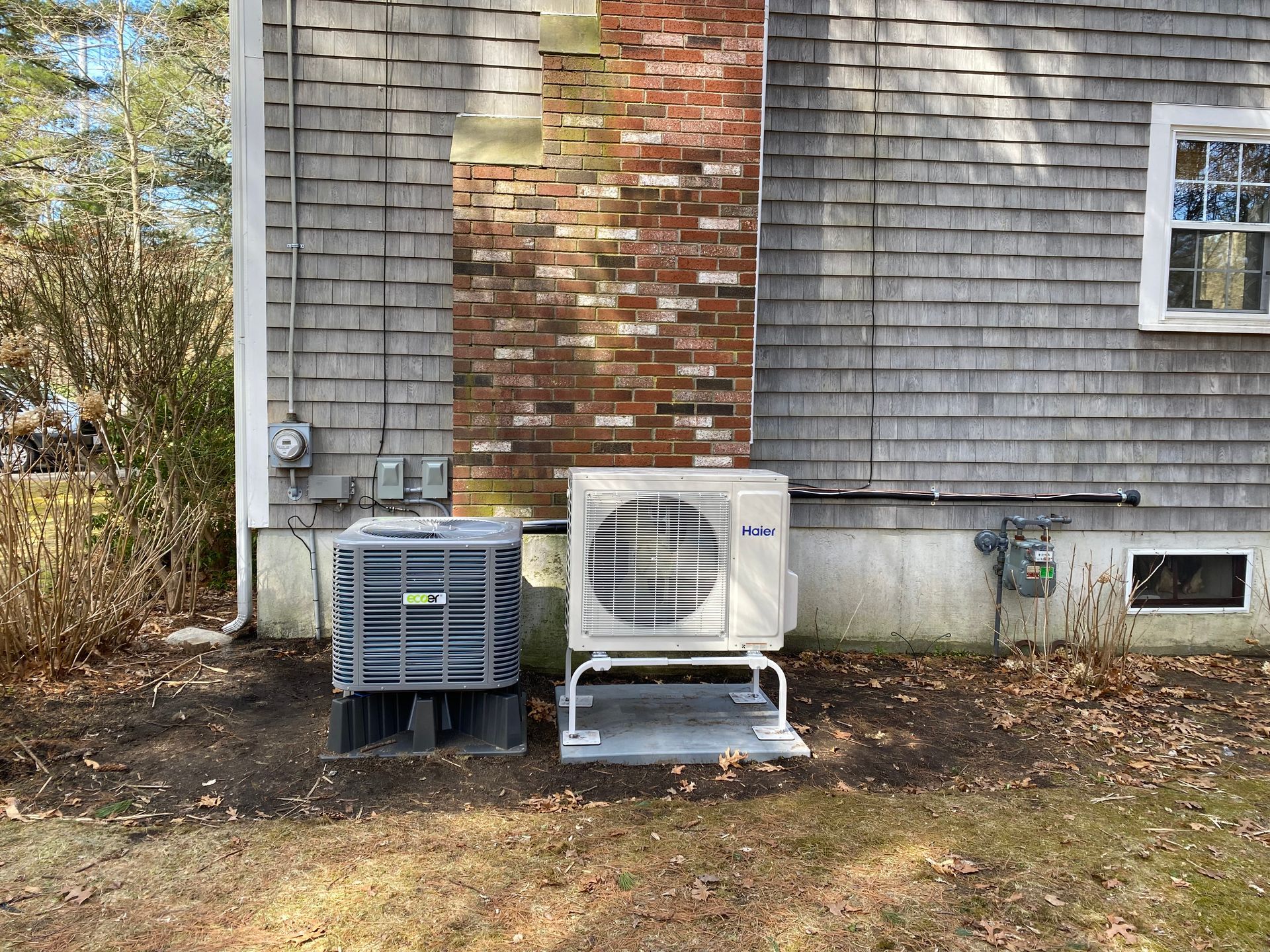 There are two air conditioners on the side of a house.