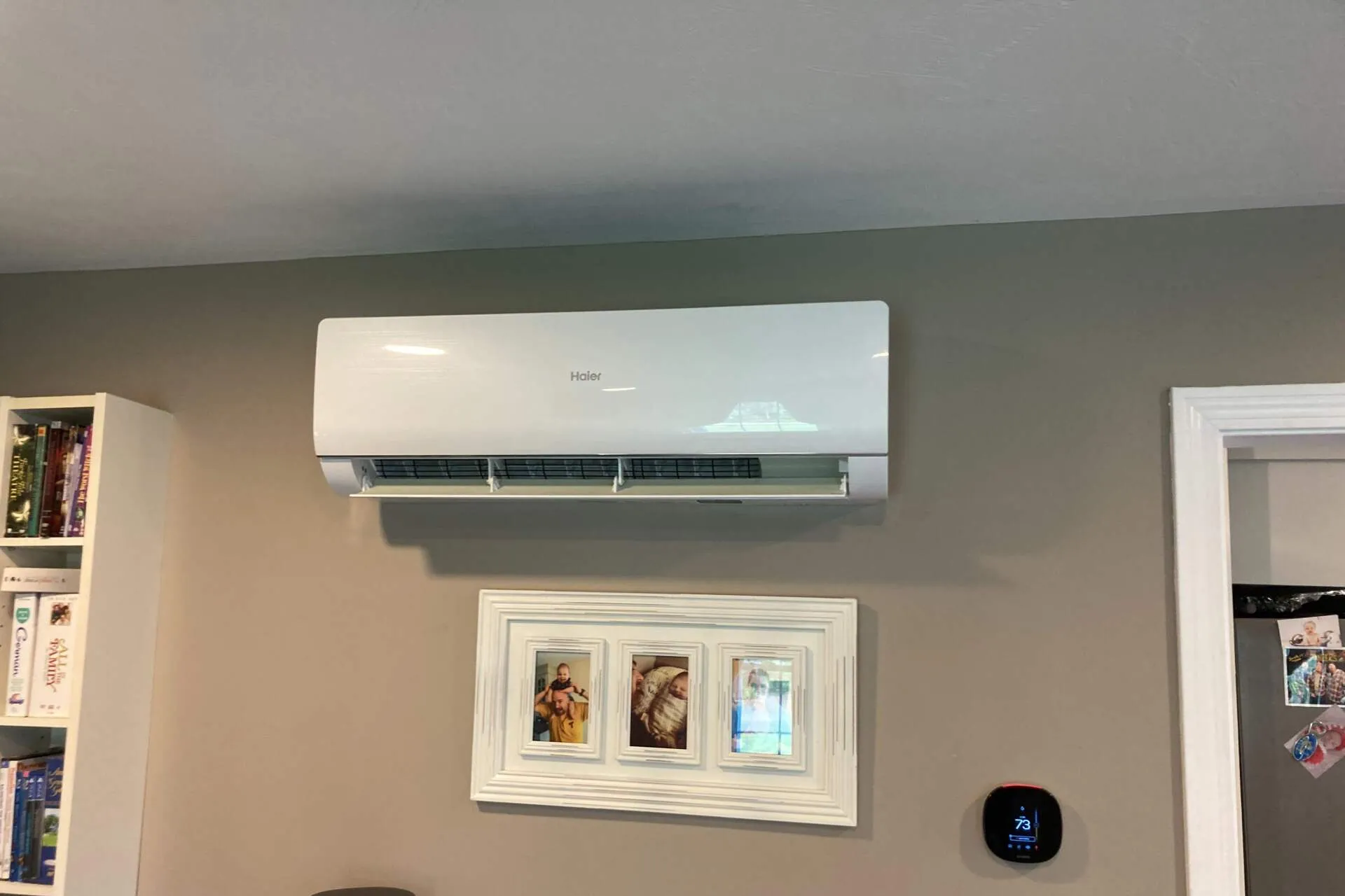 A white air conditioner is hanging on a wall in a living room.