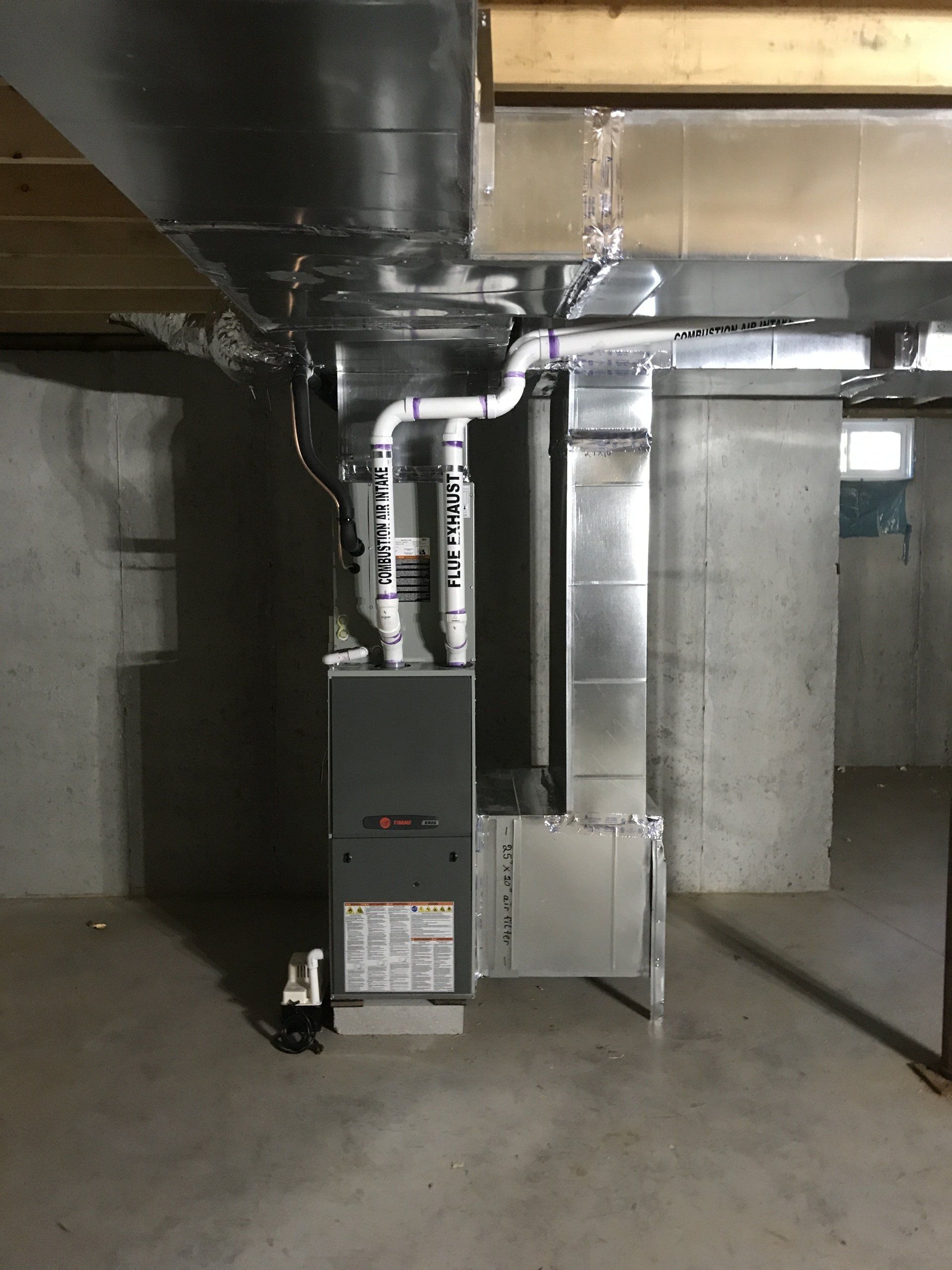 A basement with a furnace and pipes coming out of it.