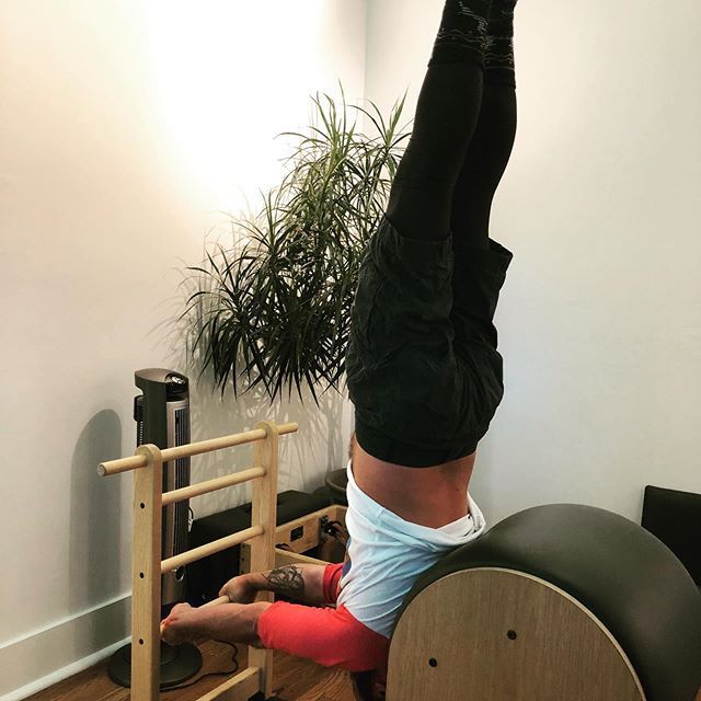 A person is doing a handstand on a pilates machine