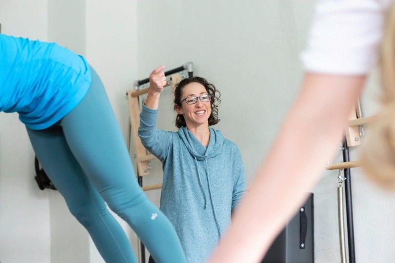 A woman is teaching a group of people how to do yoga.