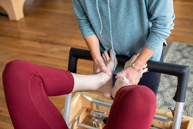 A woman is getting her foot massaged on a pilates machine.