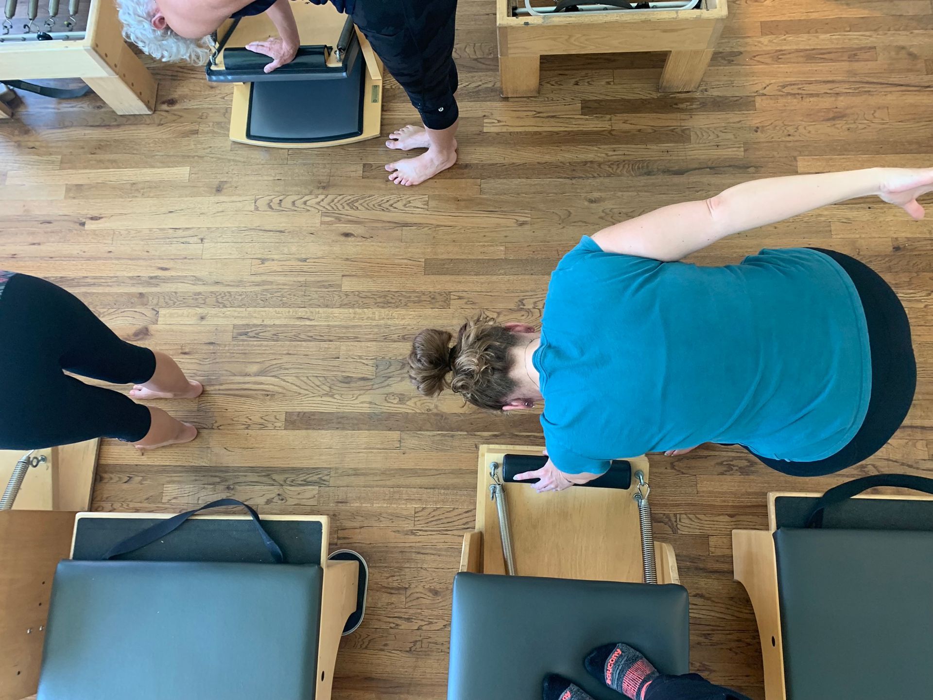 A group of people are doing exercises on pilates machines in a gym.