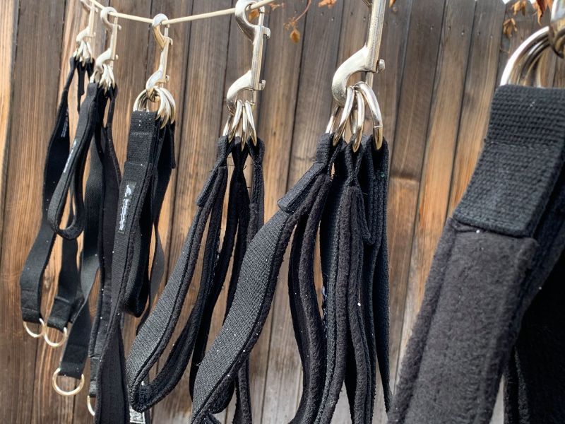 A bunch of black straps are hanging on a rope.