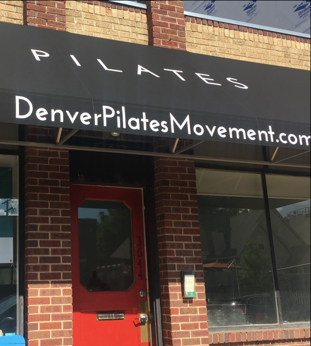 A brick building with a black awning that says denverpilates movement.com