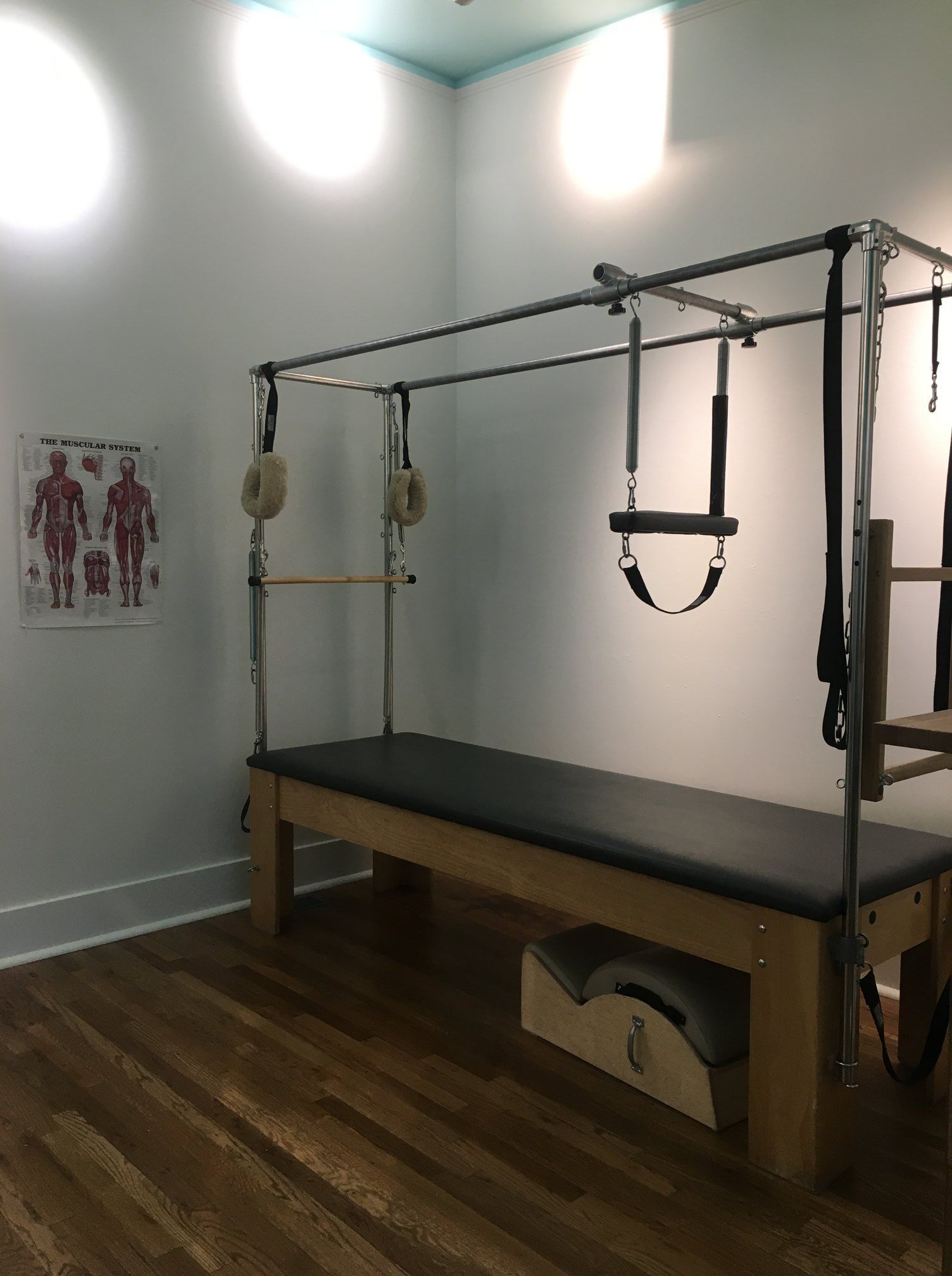 A pilates machine is sitting in a room with a wooden floor.