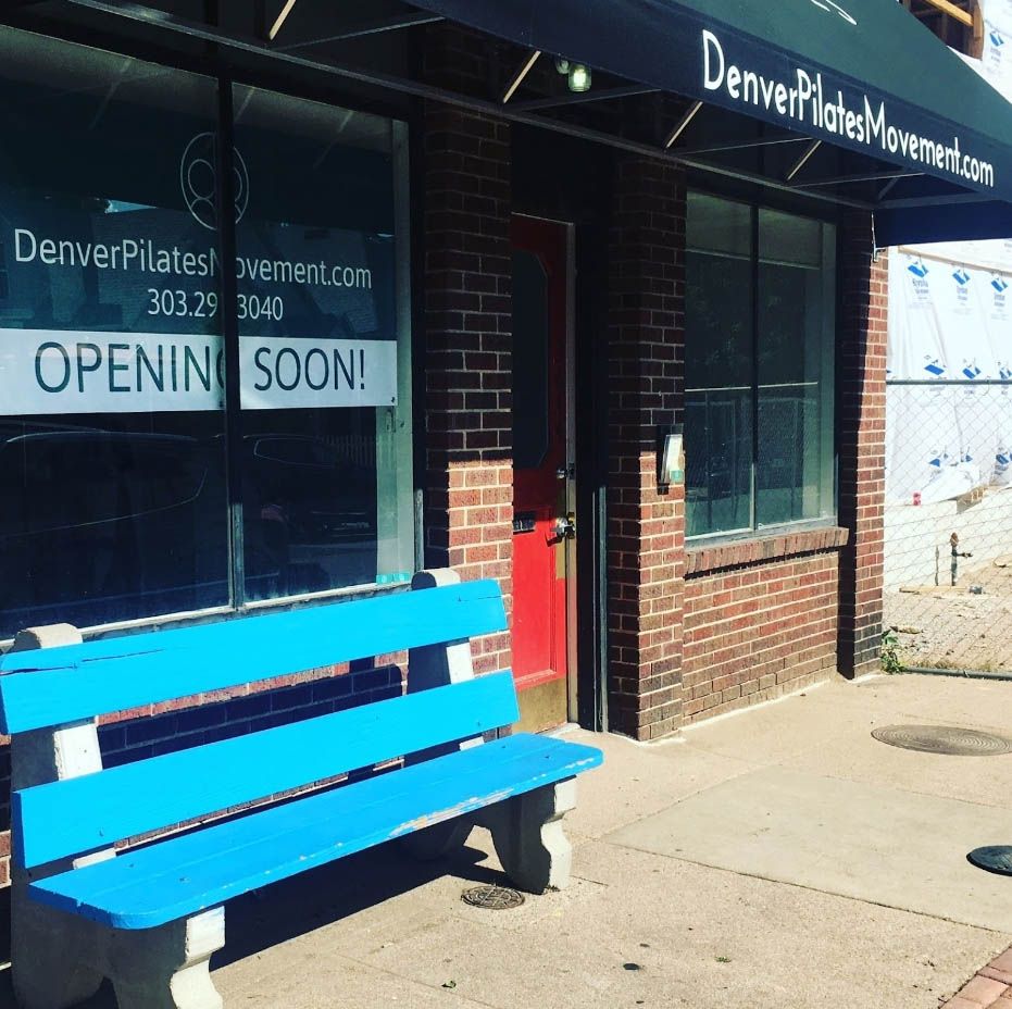 A blue bench sits in front of a denver pilates store