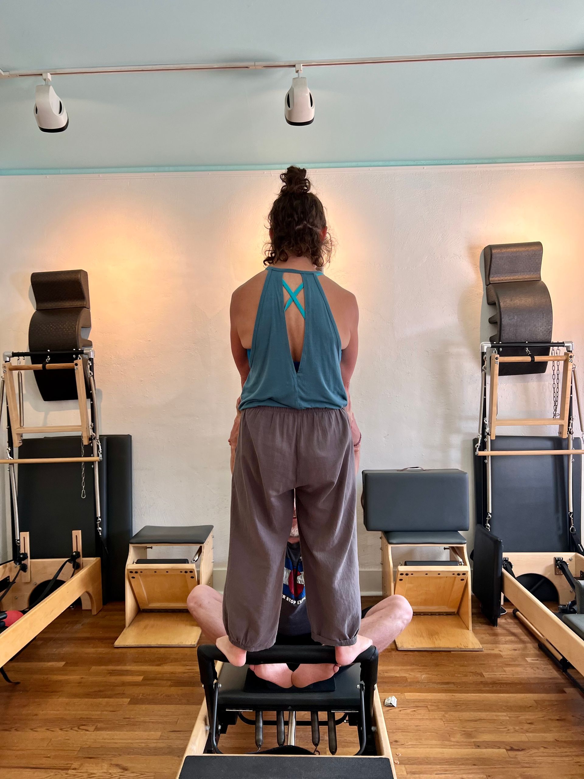 A woman is standing on a pilates machine in a gym