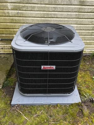 A large air conditioner is sitting on top of a concrete platform in front of a building.