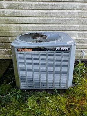 A large air conditioner is sitting on top of a concrete platform in front of a building.