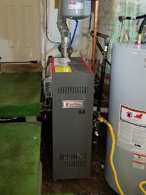 A gas heater is sitting next to a water heater in a basement.