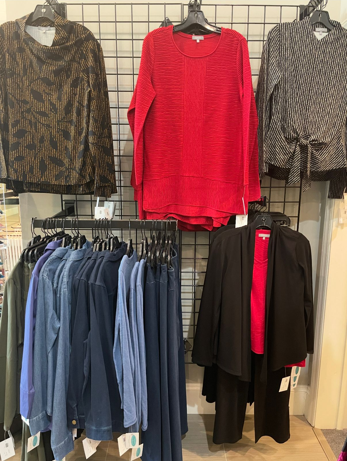 Clothing display: tops and pants in a shop. Colors include black, red, and blue.