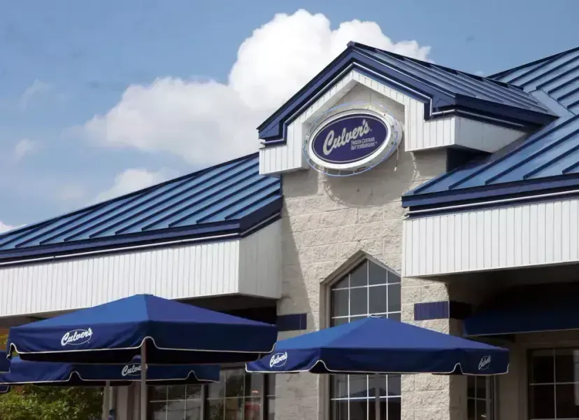 Exterior of Culver's restaurant with blue roof, white siding, and blue outdoor umbrellas.