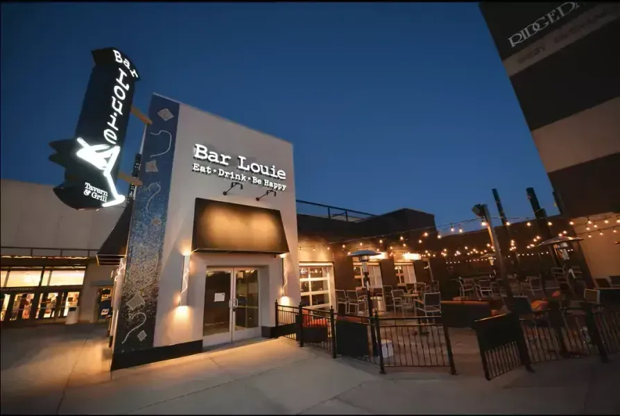 Bar Louie restaurant exterior at dusk with outdoor seating and a martini-shaped sign.