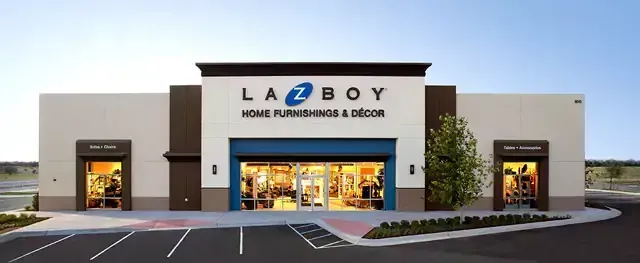 Exterior view of a La-Z-Boy Home Furnishings & Decor store, with parking lot, and displays visible through the windows.