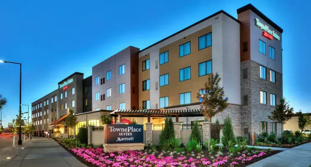 Hotel exterior at dusk with sign and landscaping.