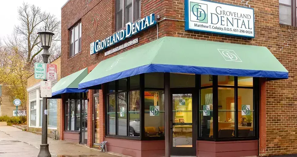 Groveland Dental office exterior with green awning, brick building, and street lamp.