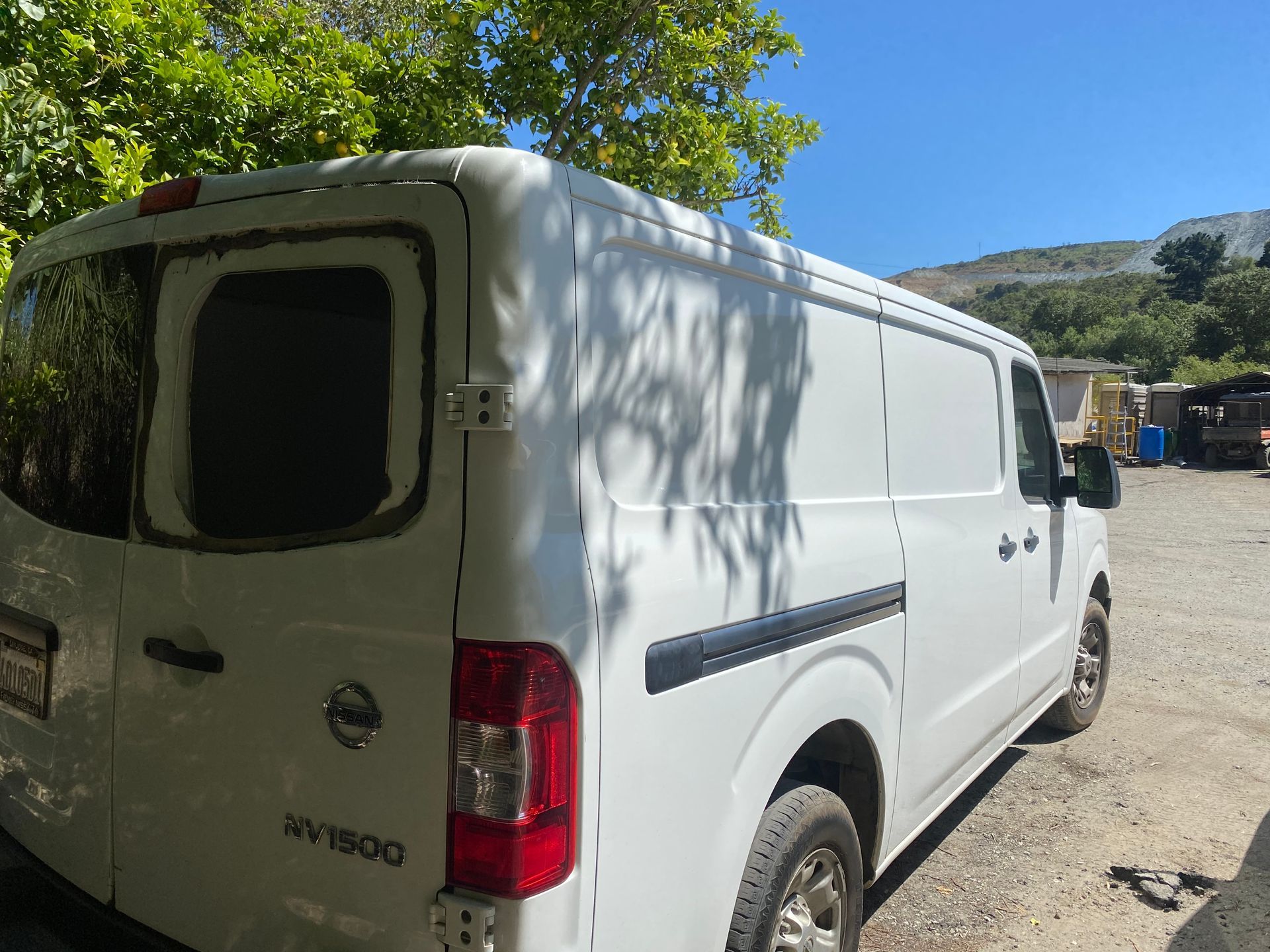White Nissan NV2500 cargo van parked outside.