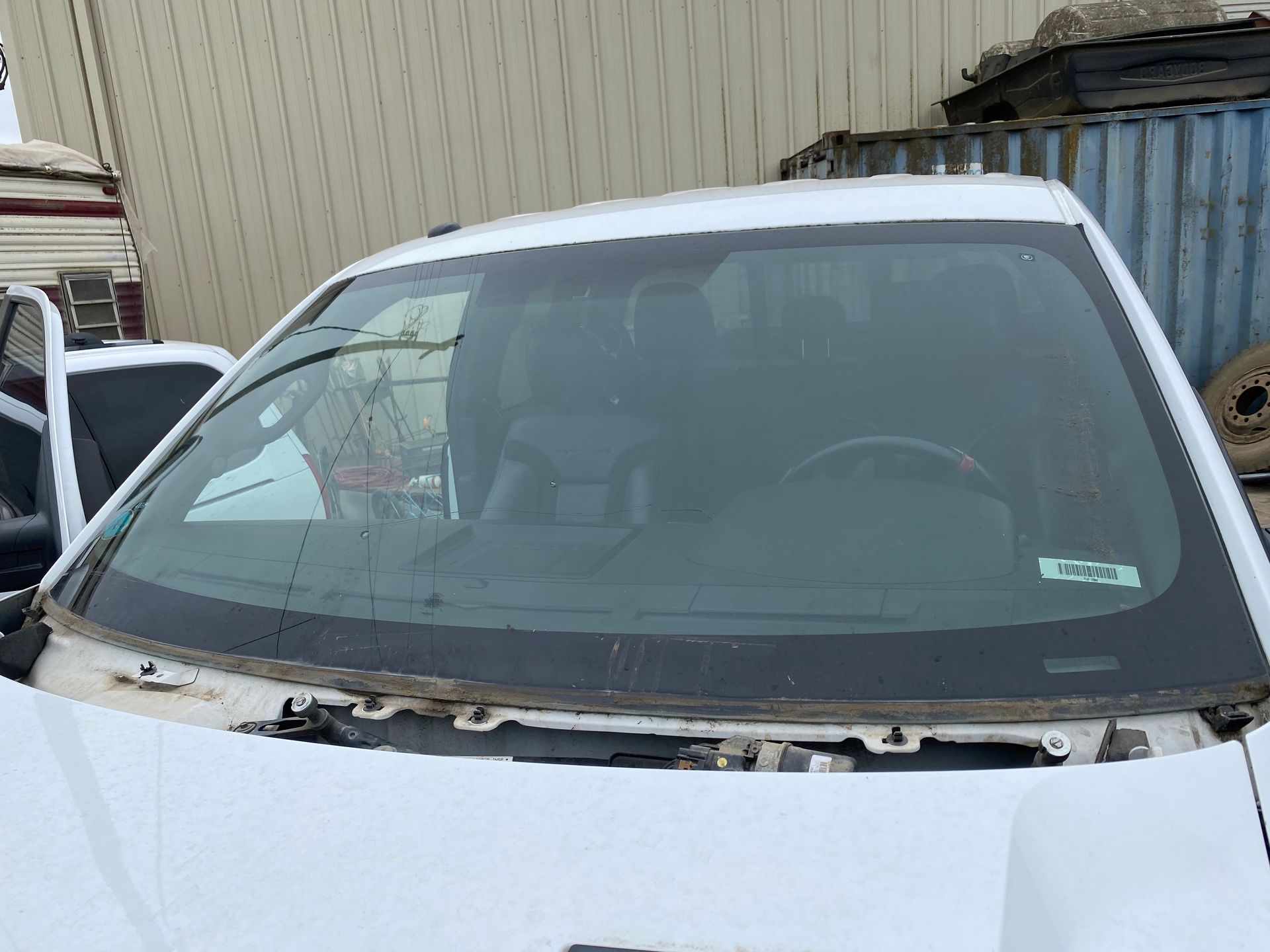 White vehicle's windshield, outdoors. Gray interior visible, the vehicle sits in a snowy environment.