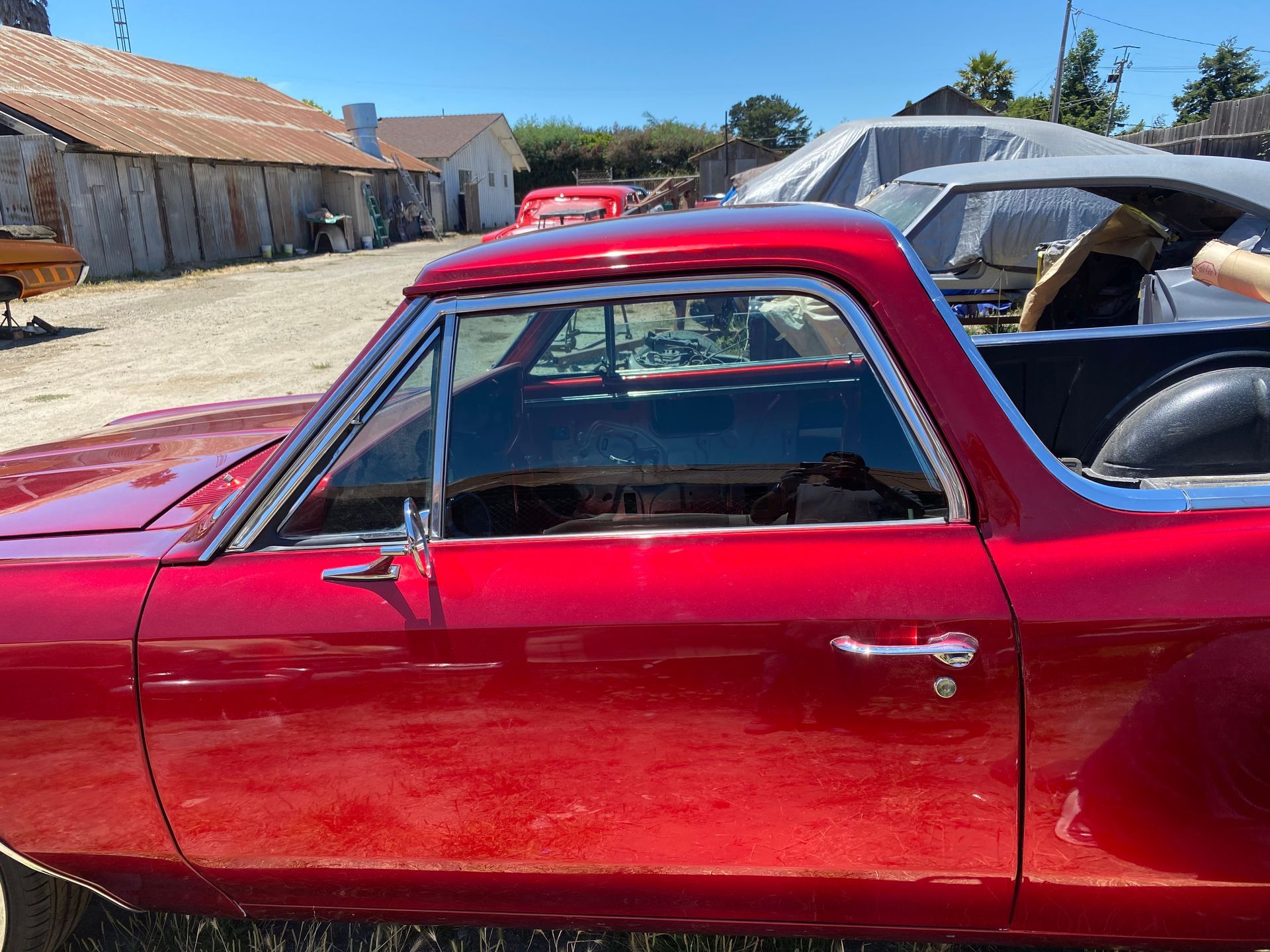 Red classic El Camino, chrome trim, parked outdoors on a sunny day.