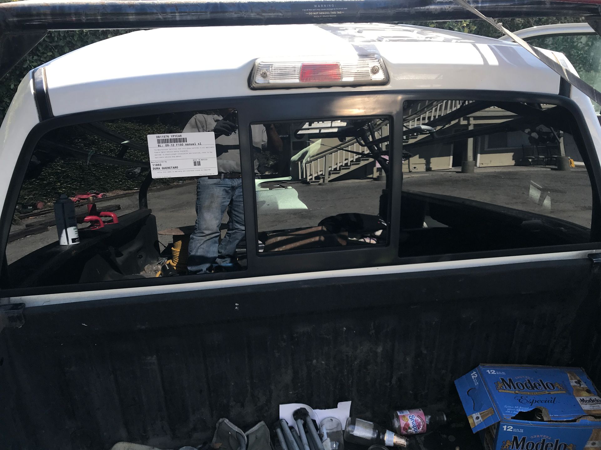 Truck bed with open rear window; tools and supplies visible; worker in background.
