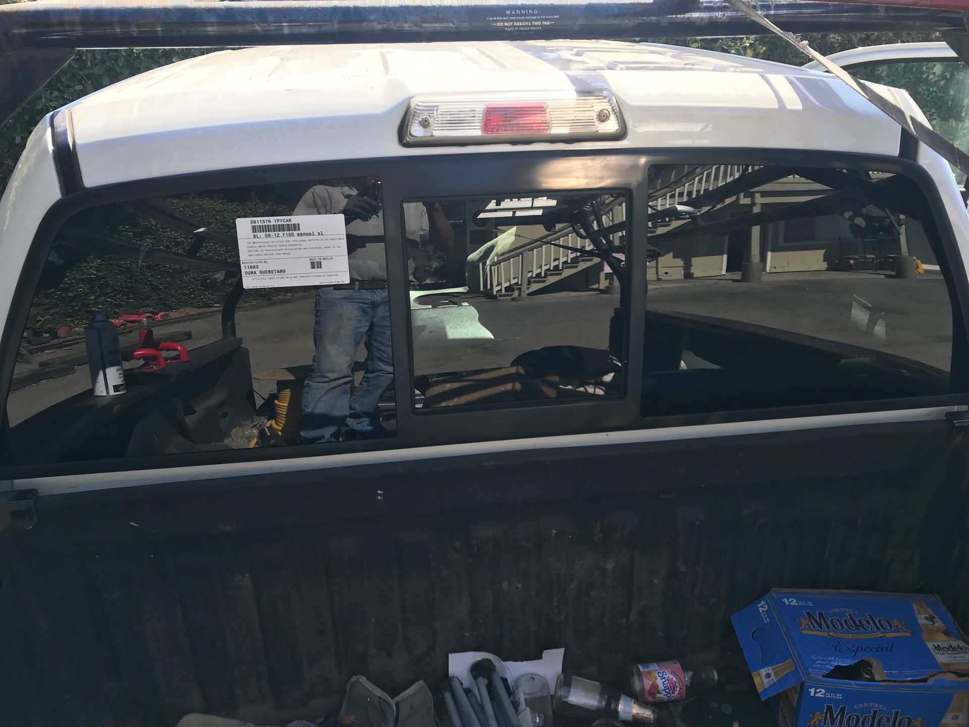 White pickup truck bed with tools and supplies. Back window with open view.