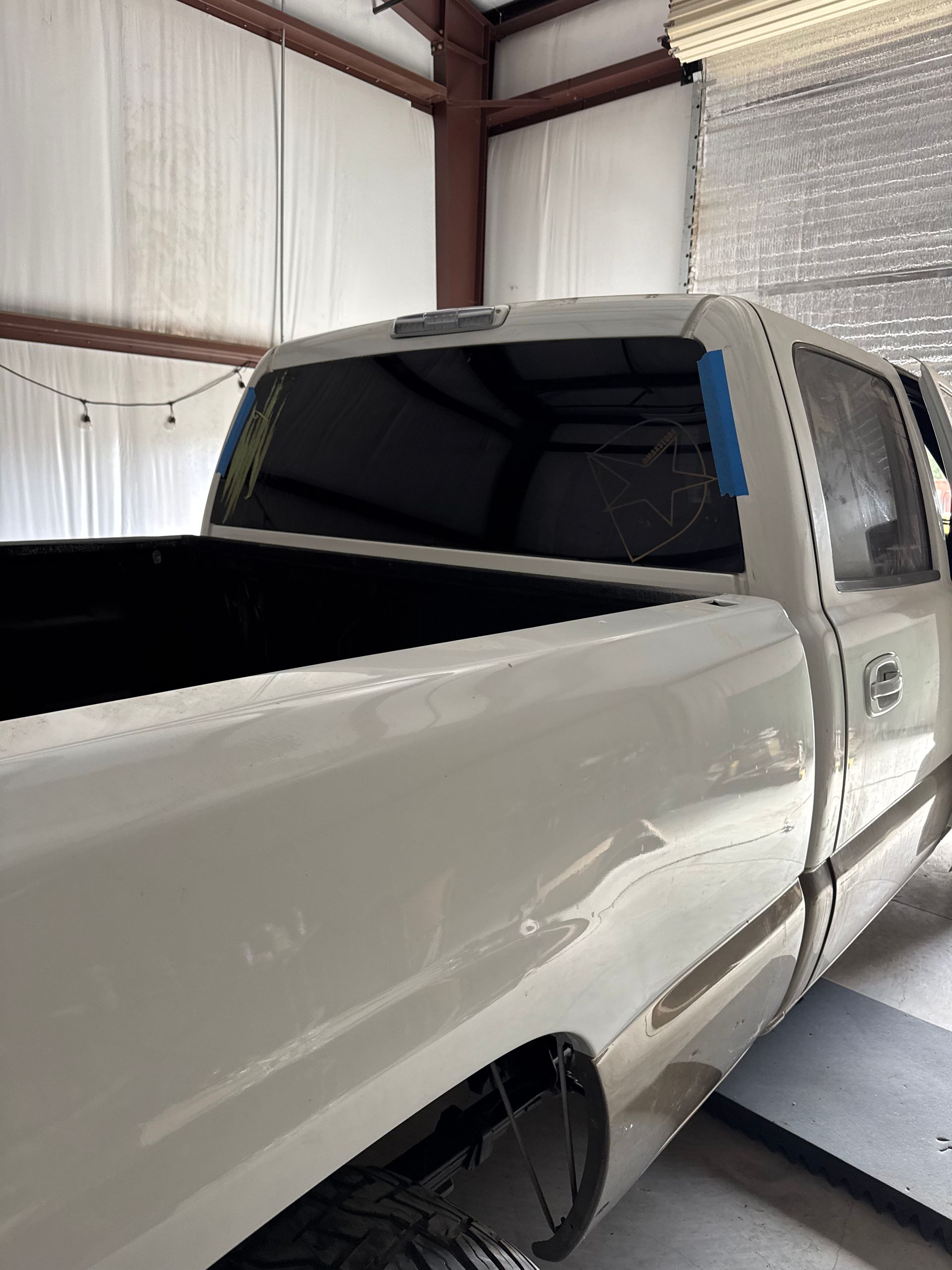 White pickup truck with tinted rear window inside a garage.