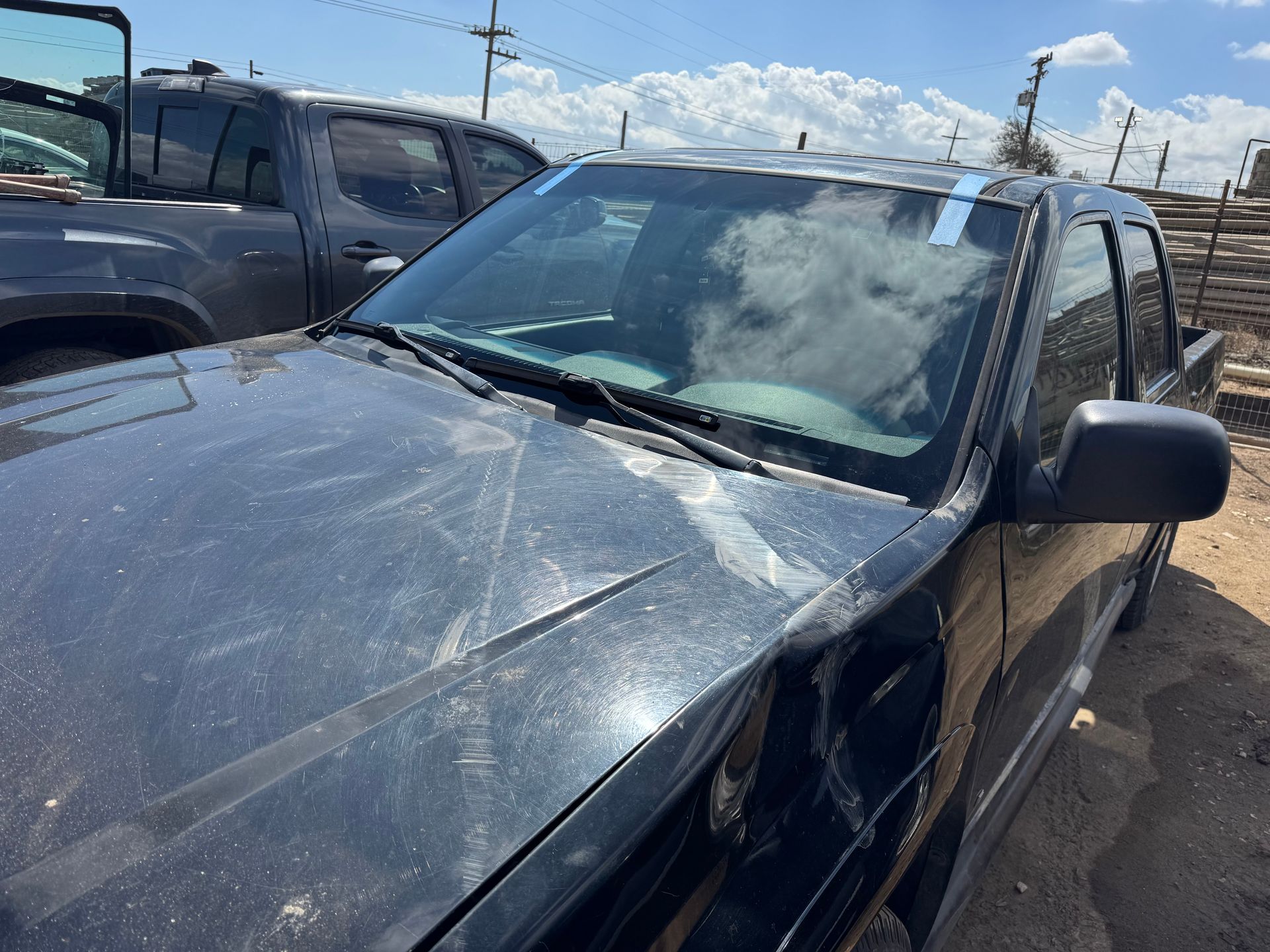 Black pickup truck, visible damage on the front end, parked outdoors.