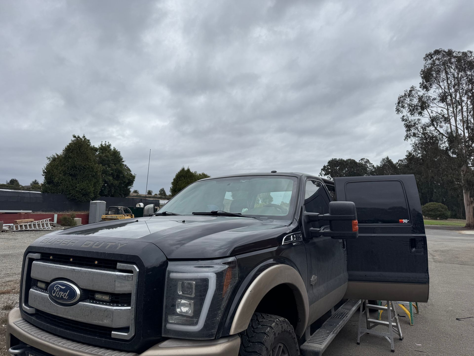 Dark Ford truck parked on a cloudy day with an open door.