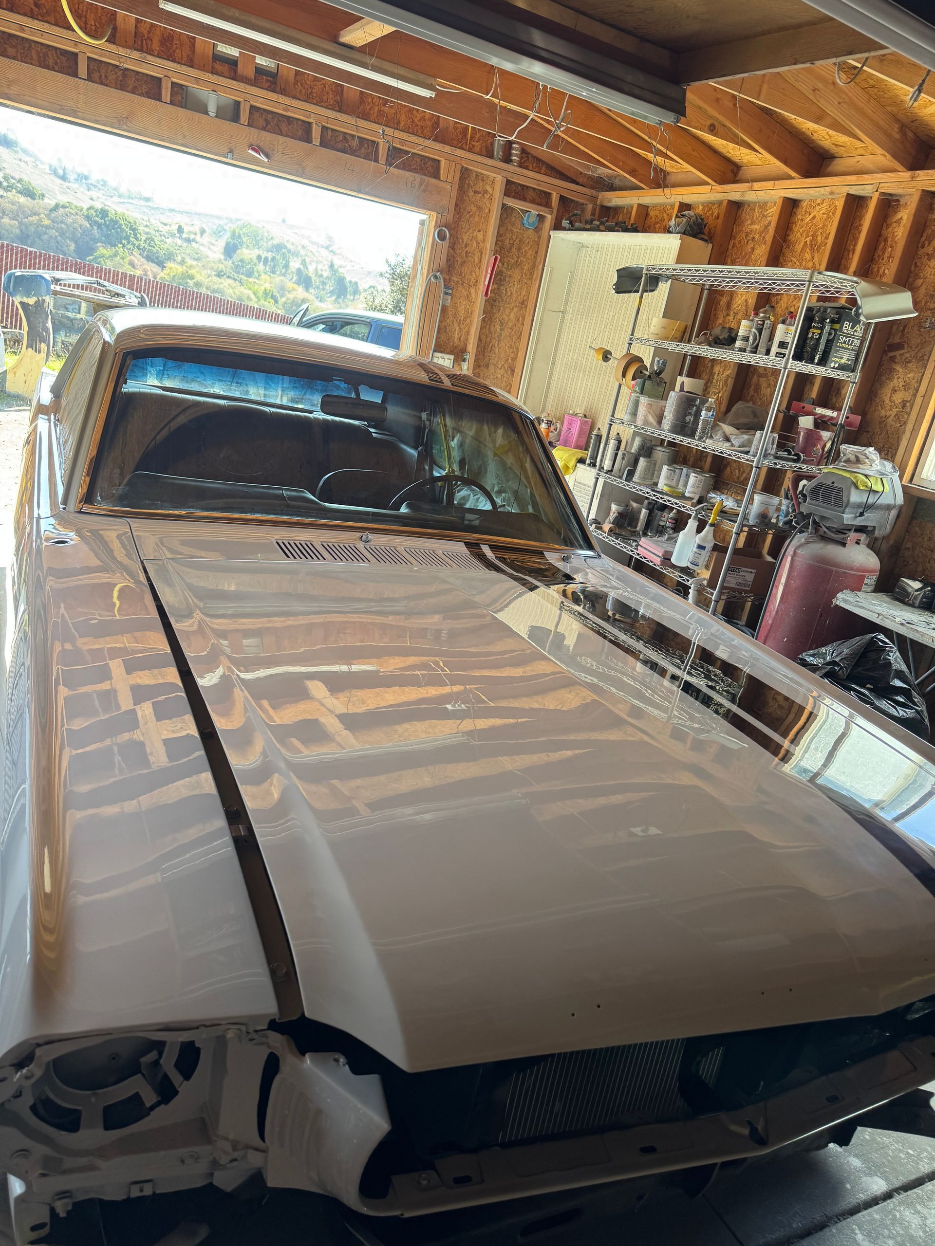 A classic white car in a garage with parts missing, likely under restoration.