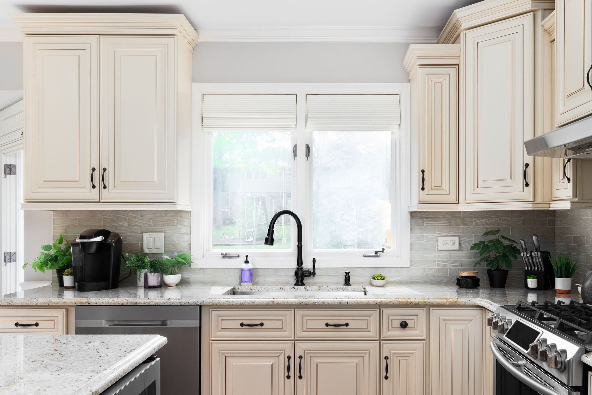 A kitchen with white cabinets , granite counter tops , stainless steel appliances and a sink.