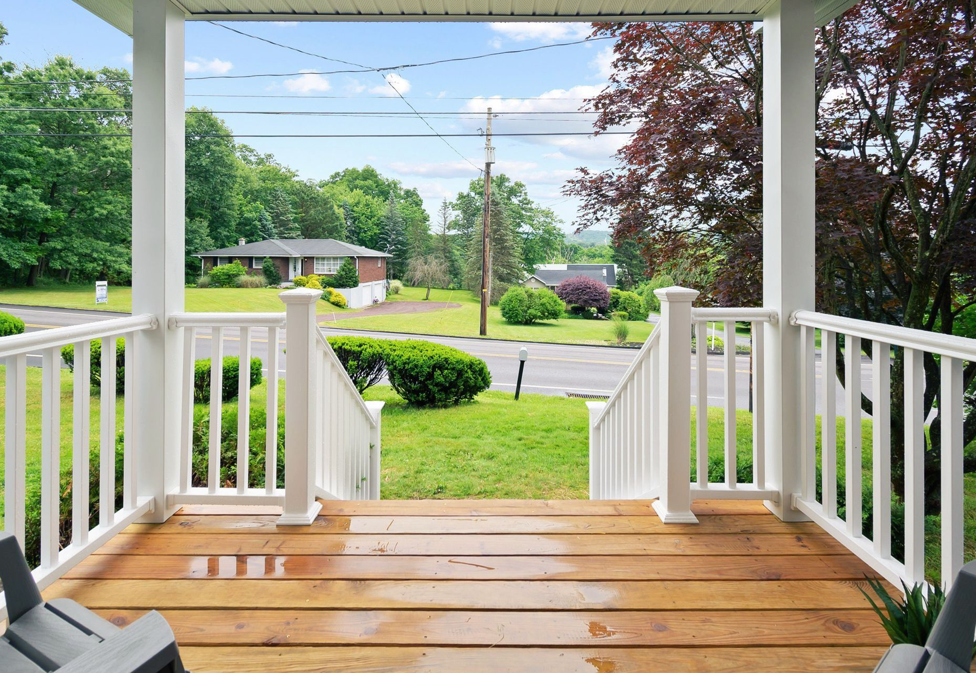 A porch with a view of a house and trees