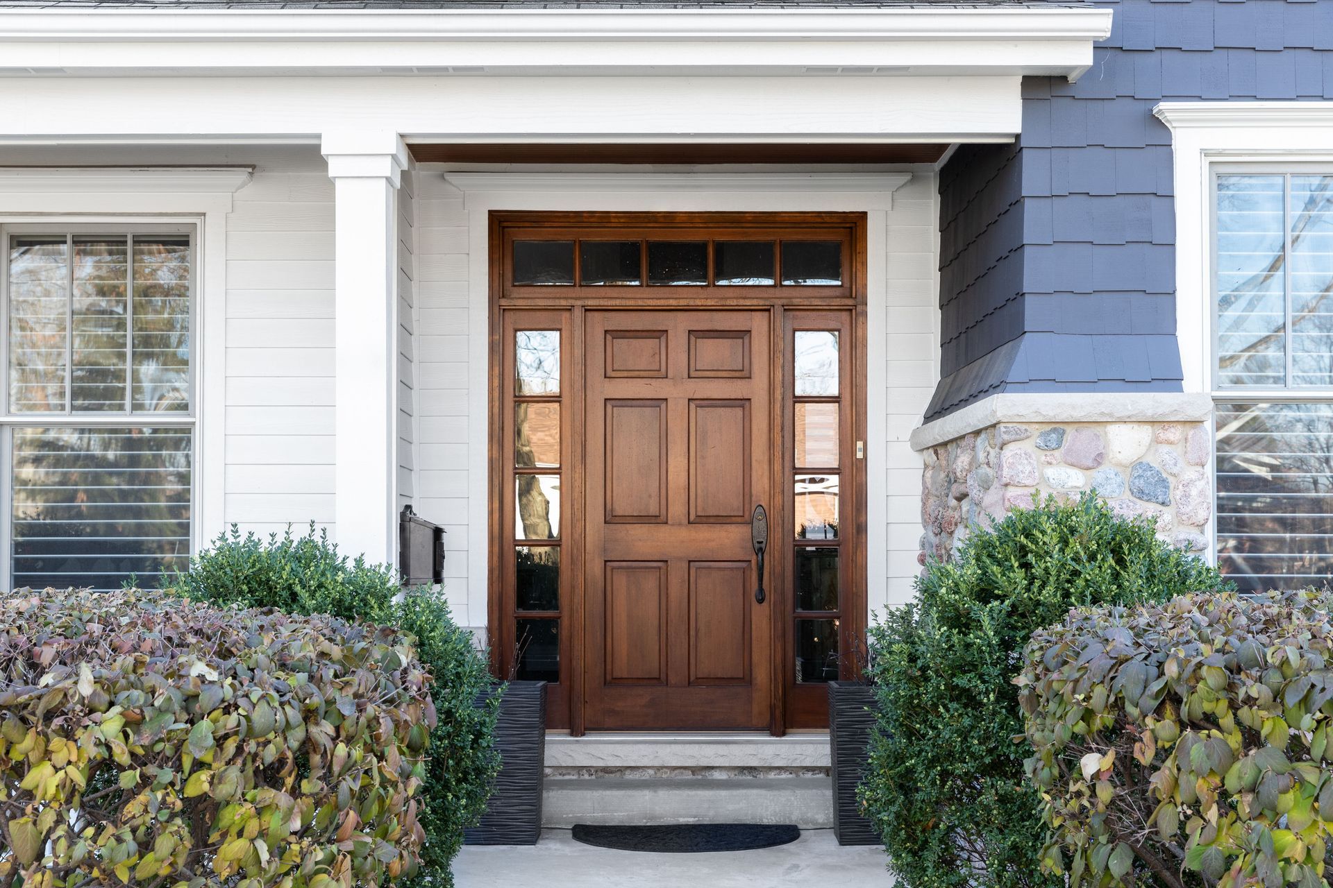 The front door of a house with a wooden door and a stone wall.