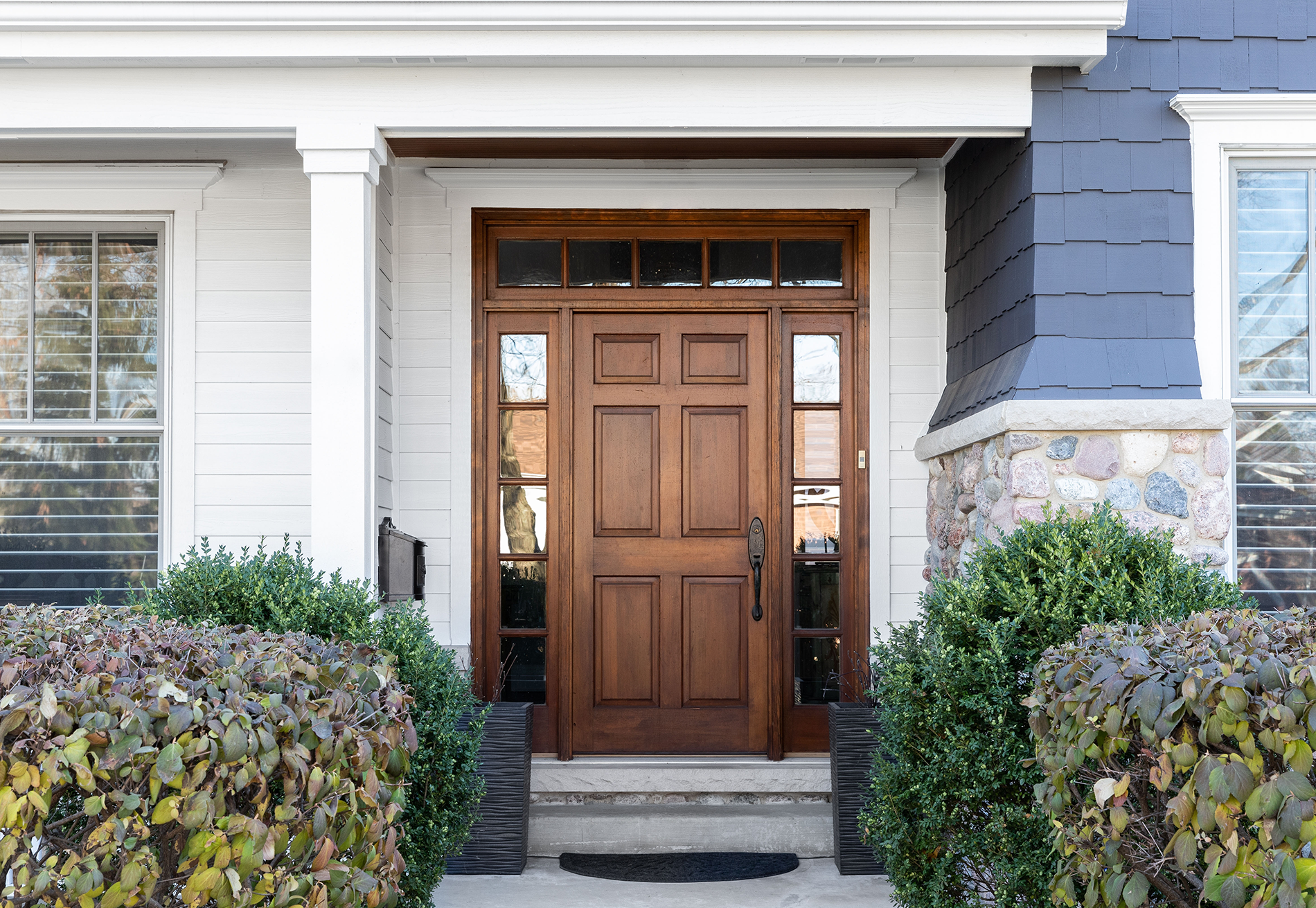 The front door of a house with a wooden door and a stone wall.